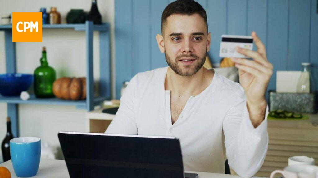 Imagem mostra jovem sentado de frente para um computador analisando dados em seu cartão.
